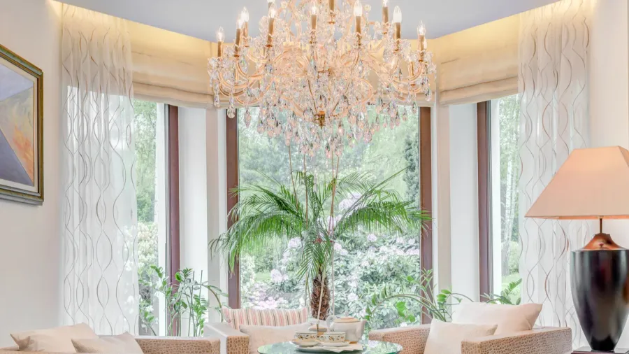 A bright living area with a chandelier, large windows, and a potted plant.