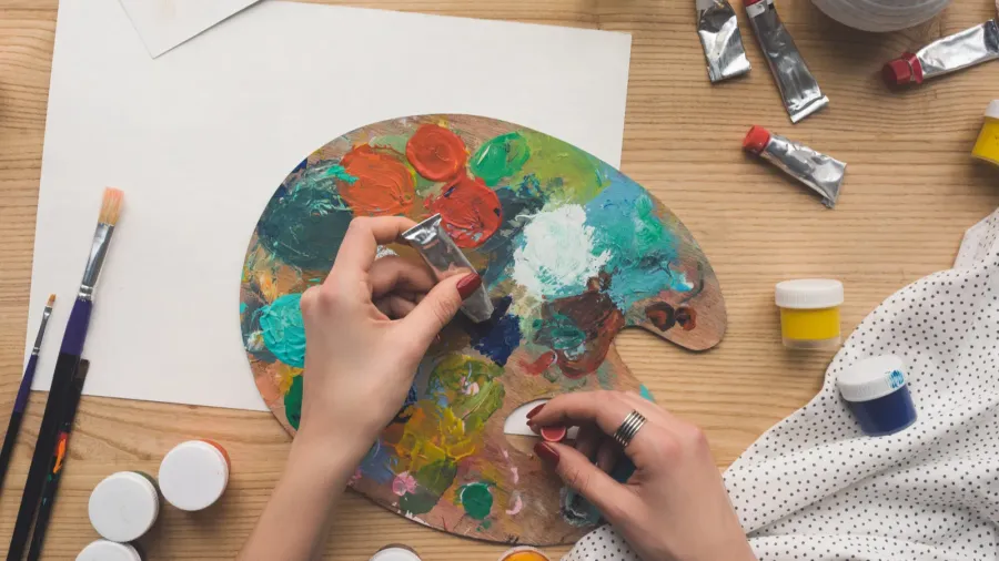 A woman mixing paints in a palette.