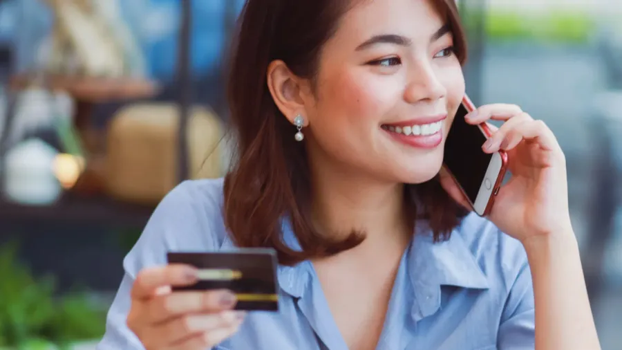 asian woman using mobile phone with credit card and laptop