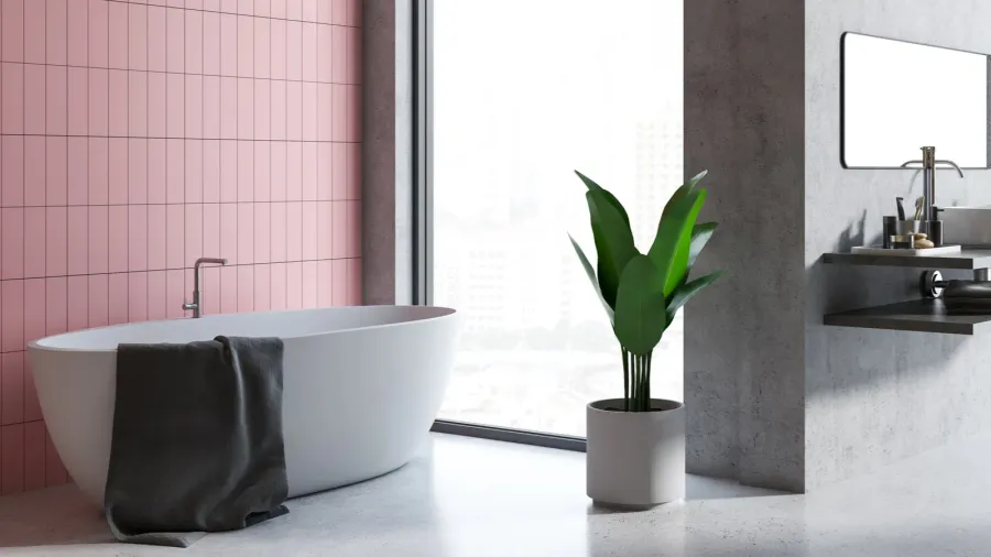 A stylish bathroom with a light pink wall, a white tub, and a potted plant beside it.