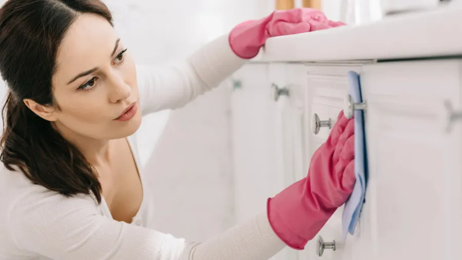 attractive housewife washing kitchen furniture with rag