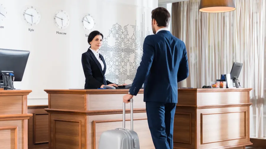 attractive receptionist looking at businessman with luggage