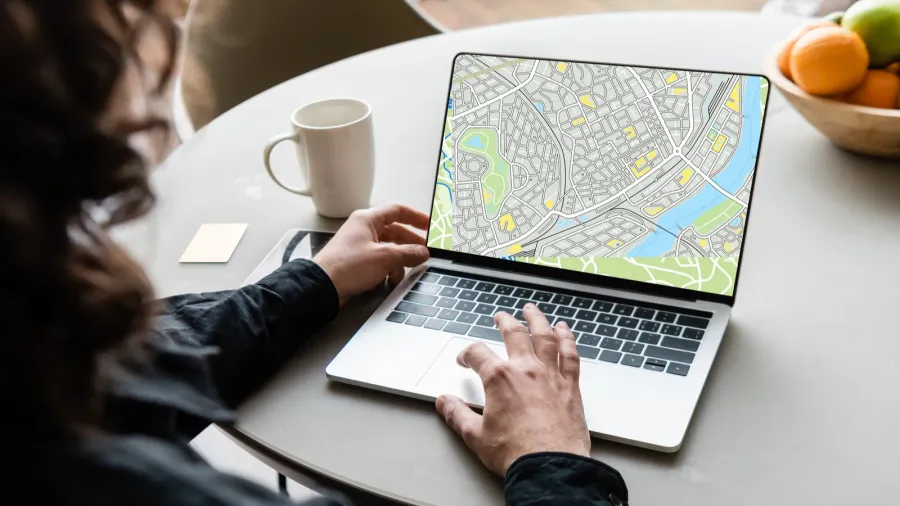 back view of freelancer using laptop with map on screen