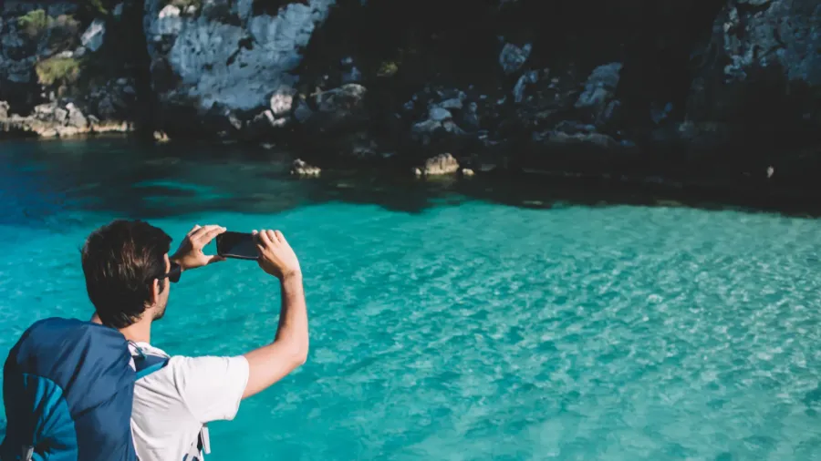 back view of male backpacker shooting video travel vlog for