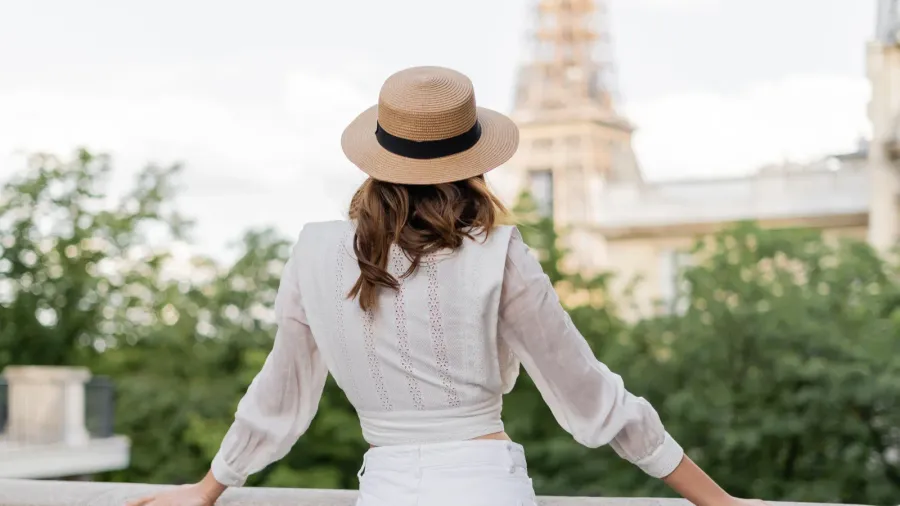 back view of tourist in sun hat standing with blurred
