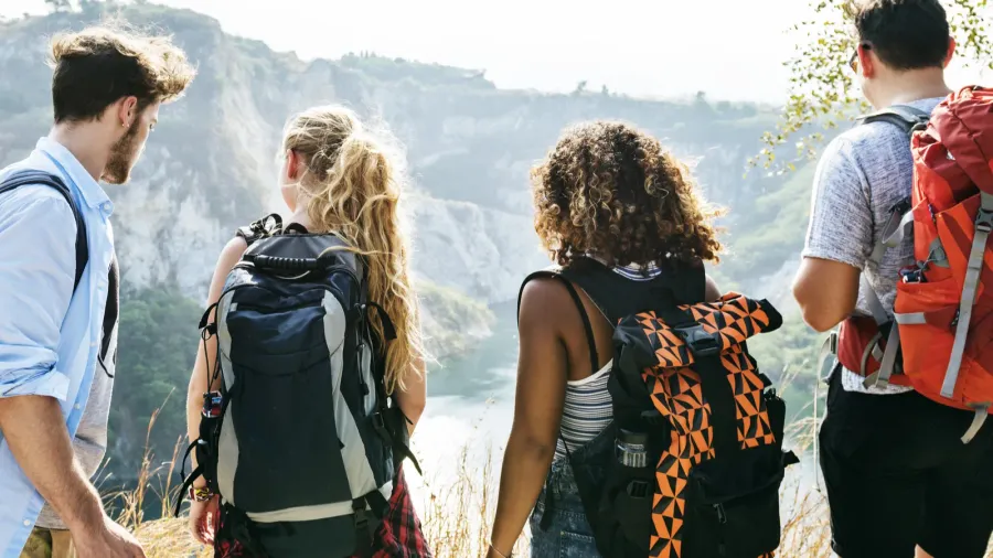 back view on friends with backpacks looking to mountains and