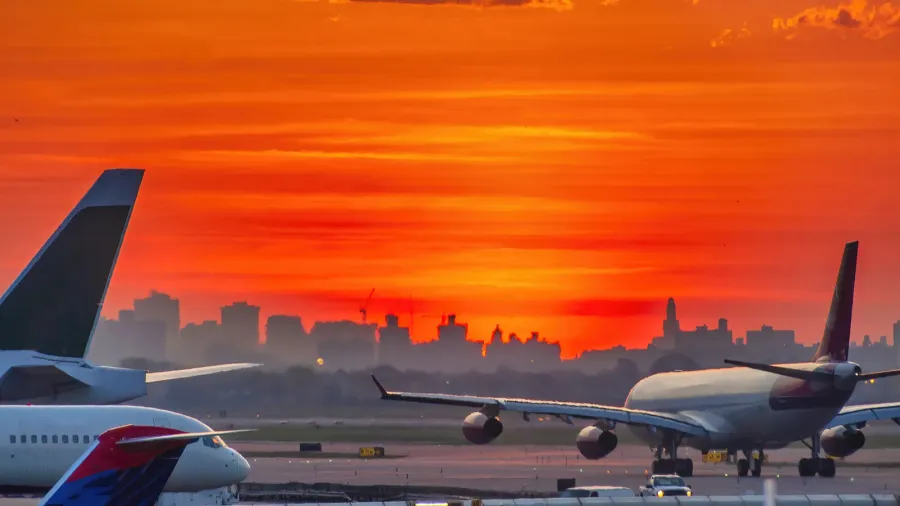 backlit view of airplanes on the airport runway at sunset
