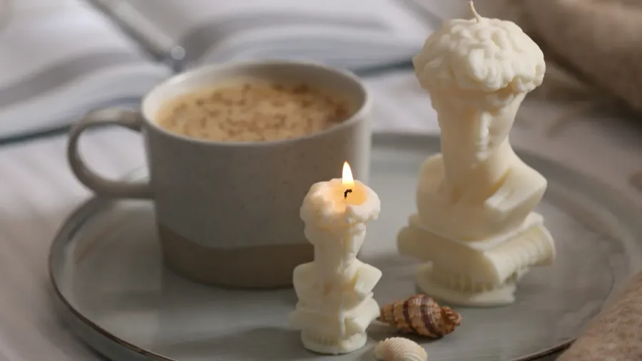 beautiful david bust candles seashells and cup of hot drink