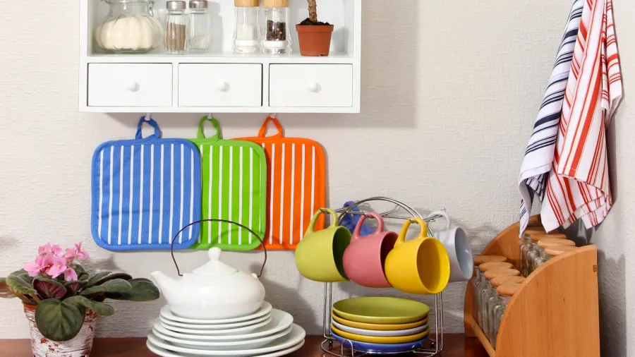 Colorful mugs, dishtowel, and kitchen towels on a counter in a kitchen.