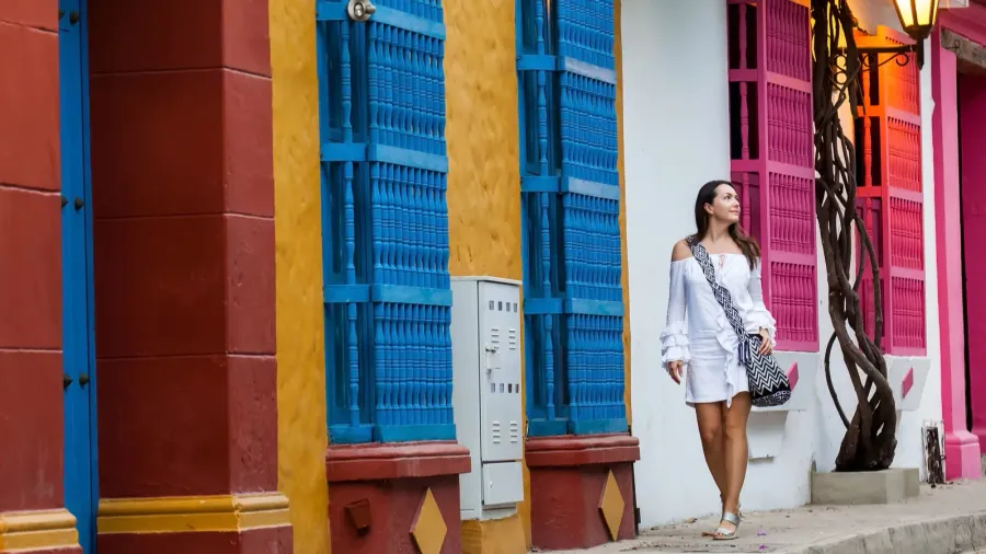Beautiful woman on white dress walking alone at the colorful streets of the colonial walled city of Cartagena de Indias