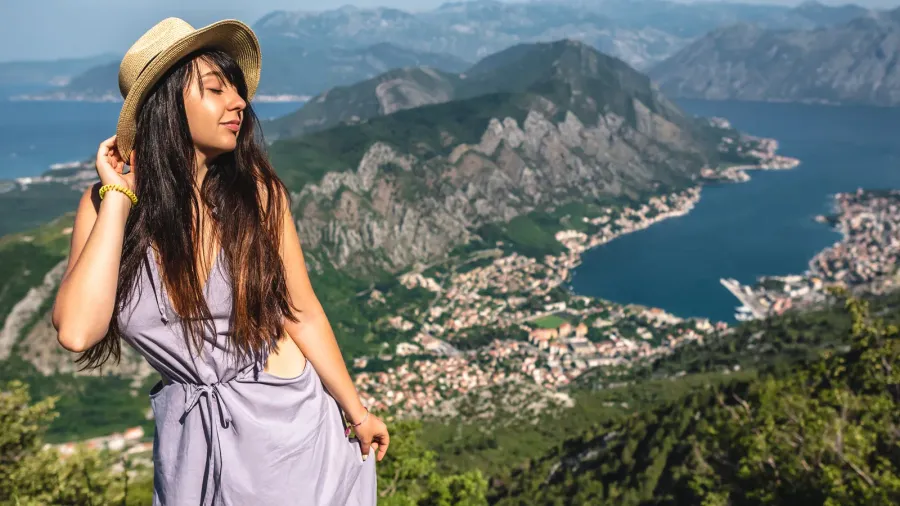 beautiful woman posing with kotor bay and kotor town on