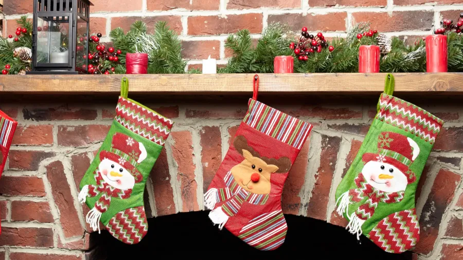 beautifully decorated santa christmas socks hanging on a fireplace in