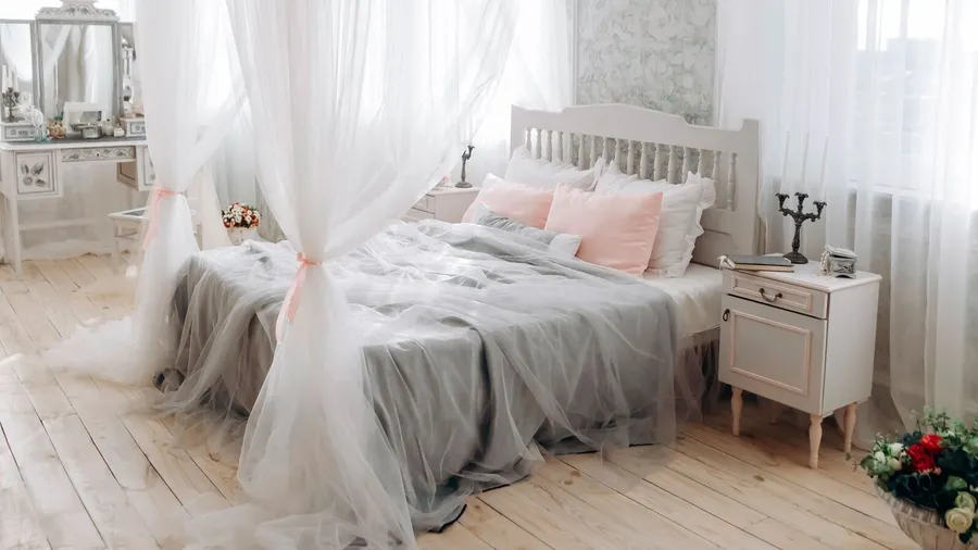 A bedroom interior with a cozy bed with pillows, blanket, and a canopy.