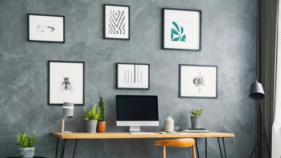 A home office interior with wooden desk, chair, and framed artwork on the wall.