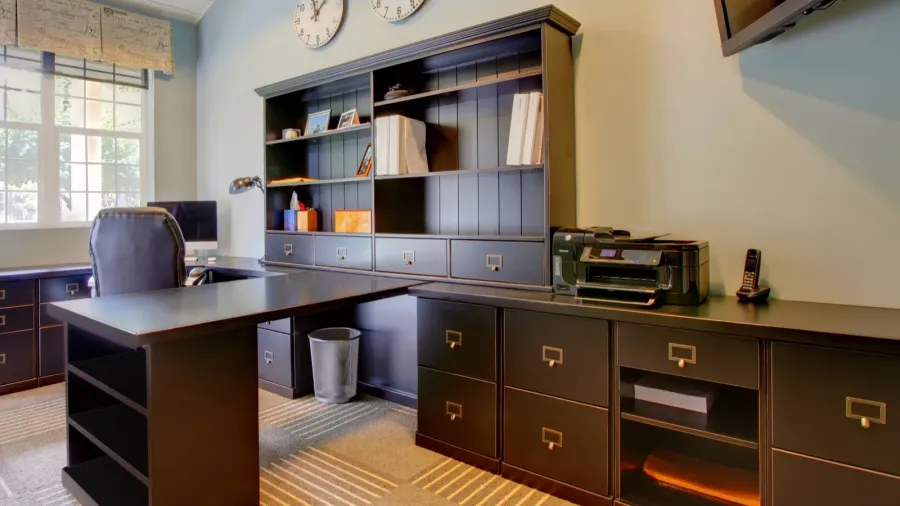 A home office interior with dark wood table and shelves.
