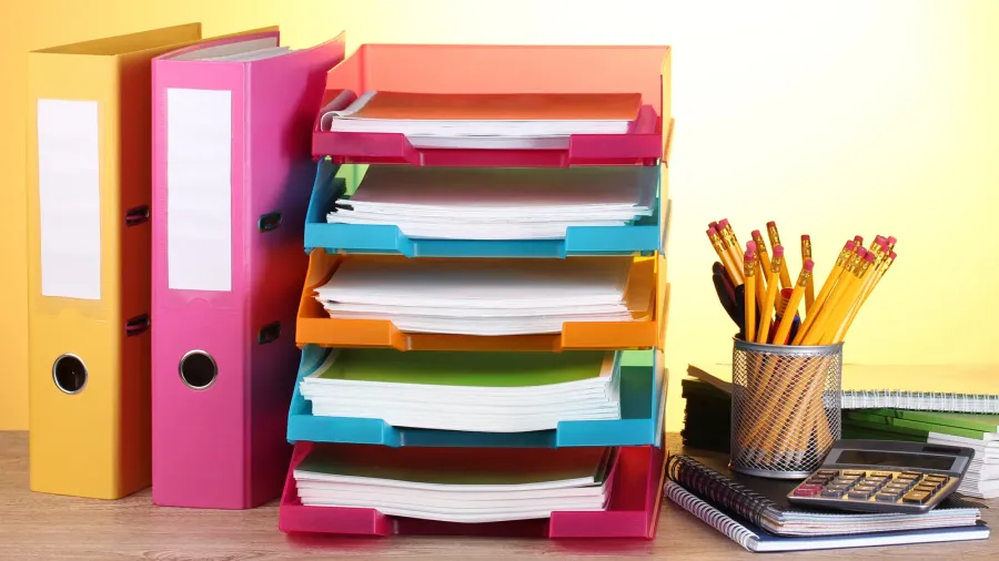 bright paper trays and stationery on wooden table on yellow