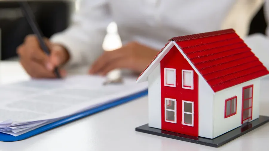 businessman signs contract behind home architectural model fema