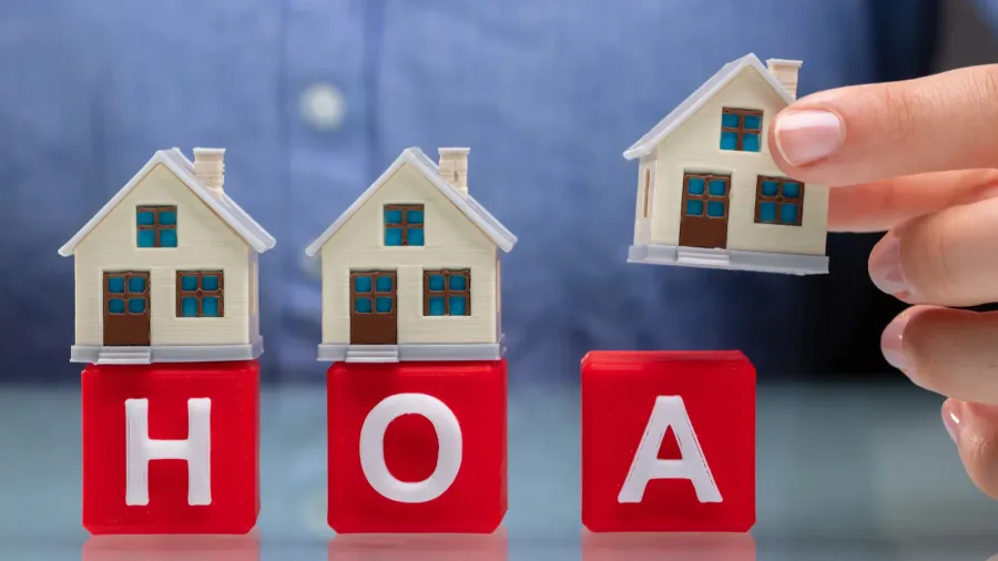 businesswomans hand placing house models on red hoa cubic blocks