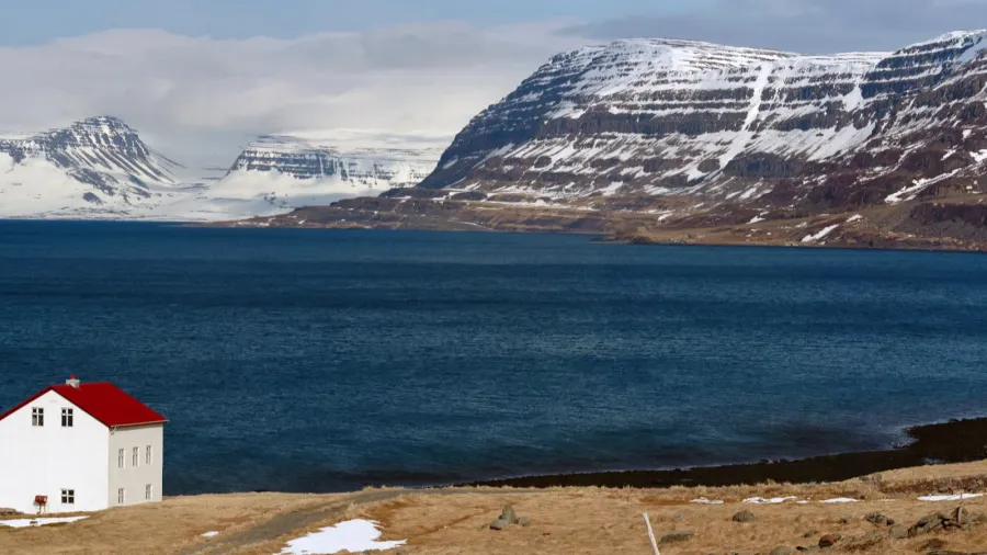 cabin near lake and snowcapped westfjords in icelandic mountains