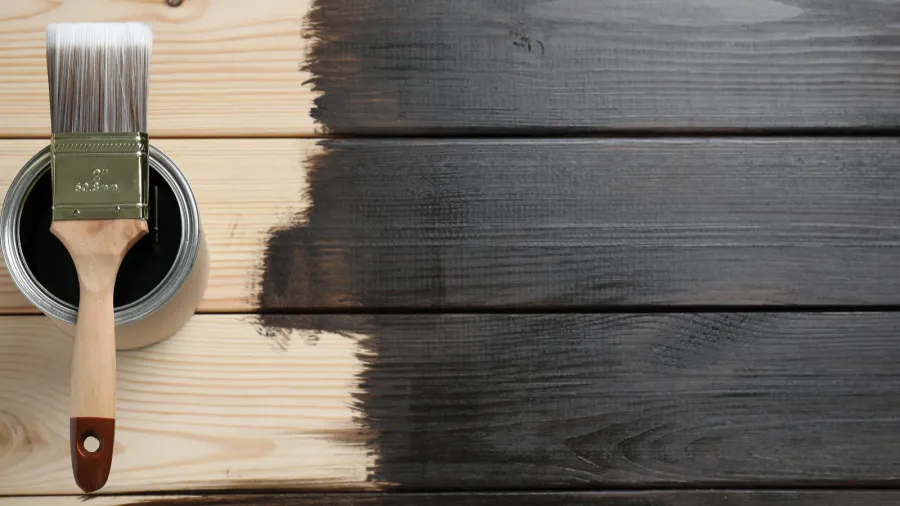 can and brush with wood stain on wooden surface top