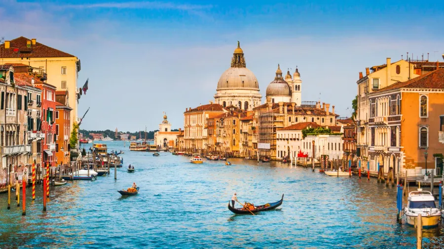 Panoramic view of famous Canal Grande and Basilica di Santa Maria della Salute in golden evening light at sunset in Venice, Italy.