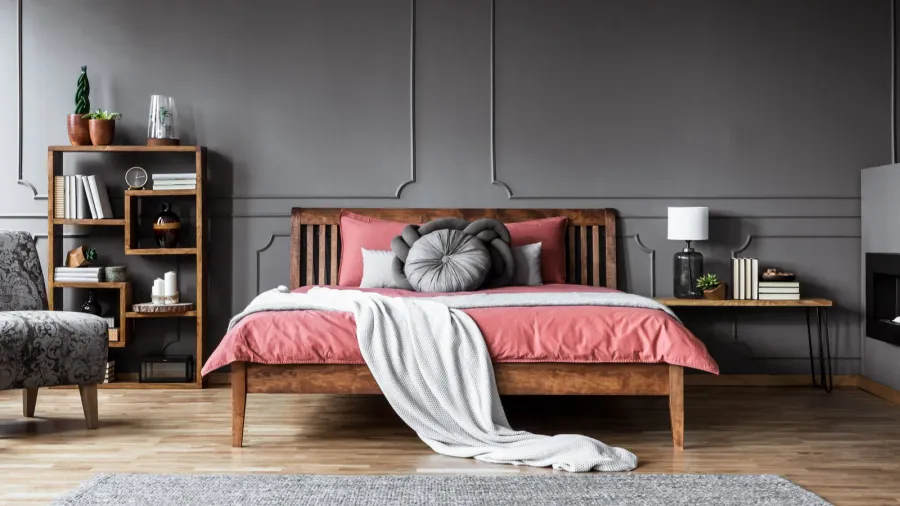 Spacious bedroom interior with grey walls, pink bedding, and wooden furniture, featuring a cozy carpet.