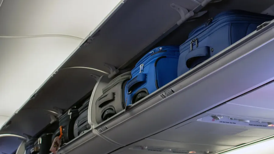 carry on luggage is stowed in overhead bins on a
