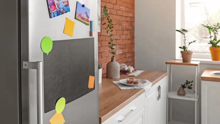 A chalkboard and sticky notes sticking on a fridge in a kitchen.