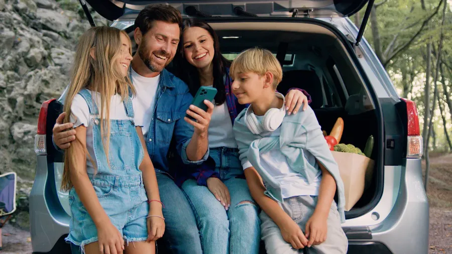 cheerful lovely parents with cute teen kids which using mobile