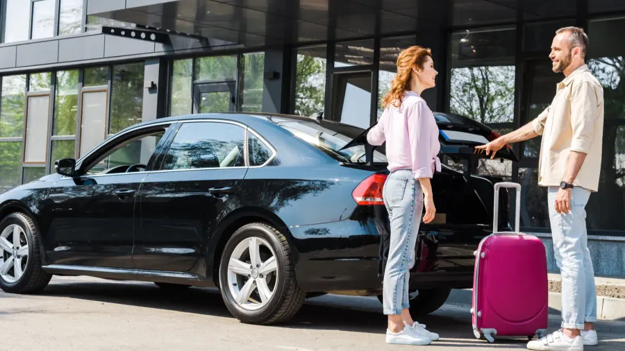 cheerful man looking at happy woman while standing near car