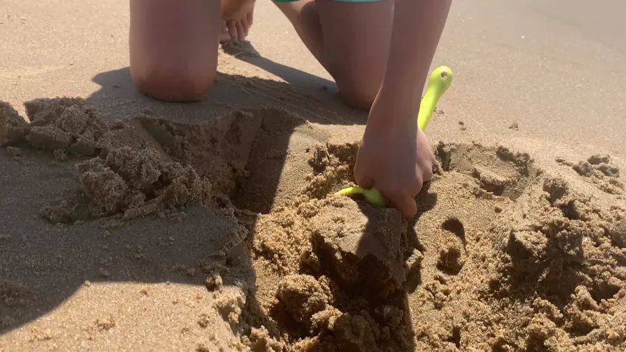 child making hole at beach with shovel kid enjoying summer