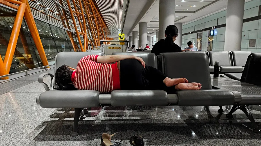 chinese woman sleeping on a bench at the airport terminal