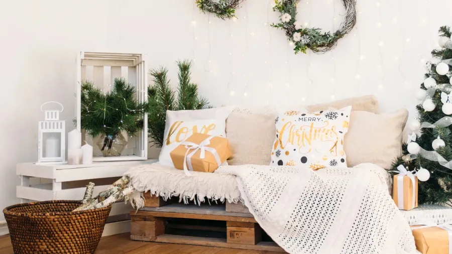 Christmas decor holiday mood in a white Scandinavian-inspired room. Throws, cushions, gifts, Christmas tree, wreaths, lanterns and candles used as decor.