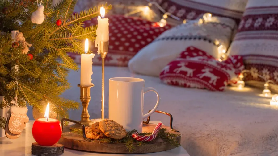 Christmas home decorations with candles and cushions in red and white colors.