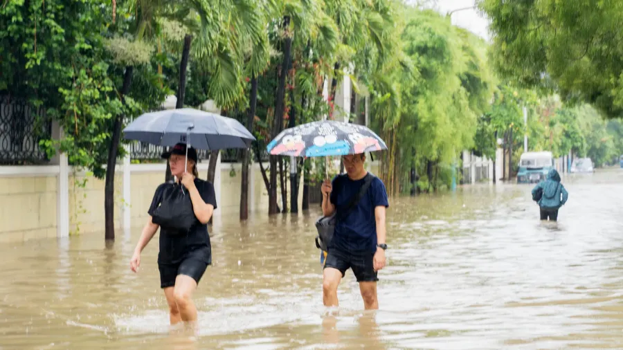 citizen crossing through puddles with umbrella