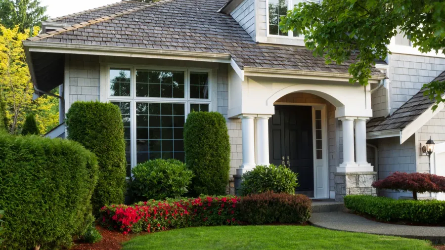 A beautiful house with well-maintained garden and lush greenery in front.