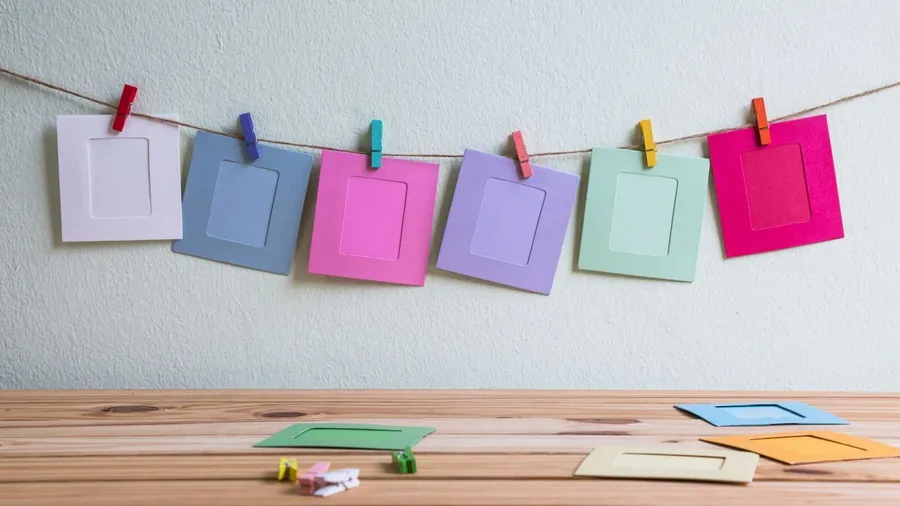 DIY colorful paper frames hanging on twine with clothespin.