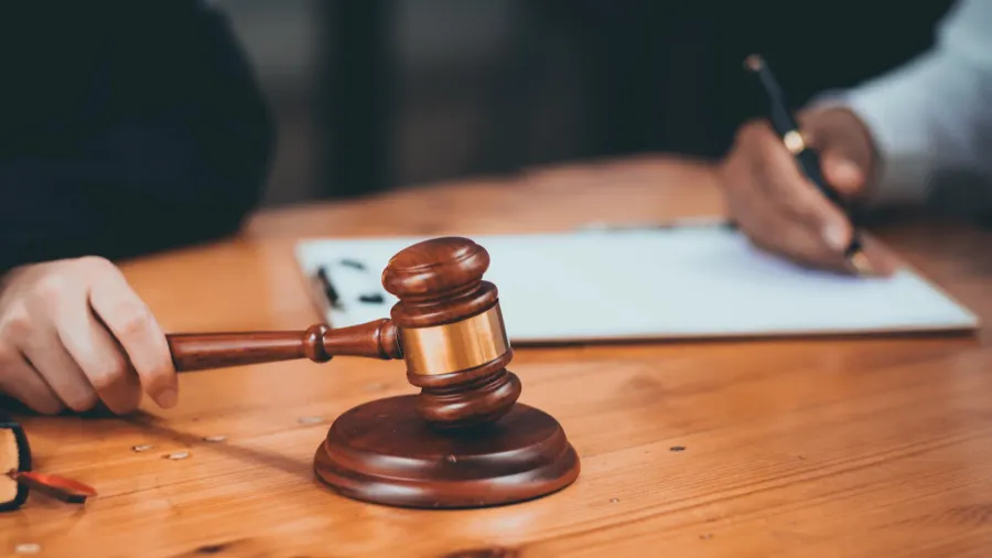 Close-up of gavel near woman with clipboard.