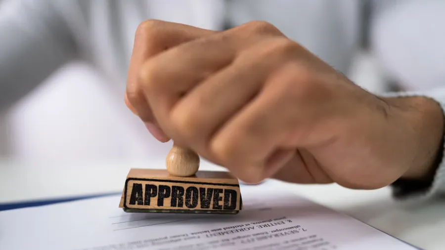 closeup of a persons hand stamping with approved stamp on