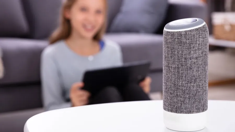 closeup of a wireless speaker on furniture with girl in