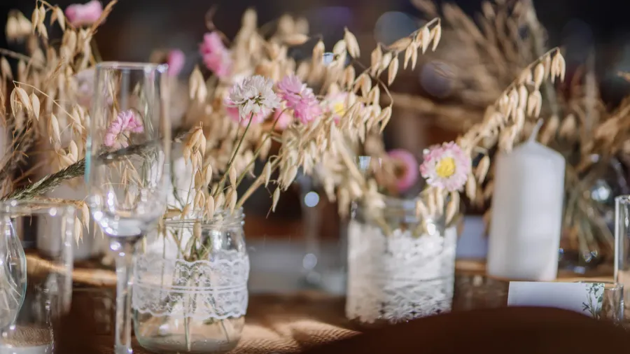 closeup of rustic table decor with glass jars wrapped in