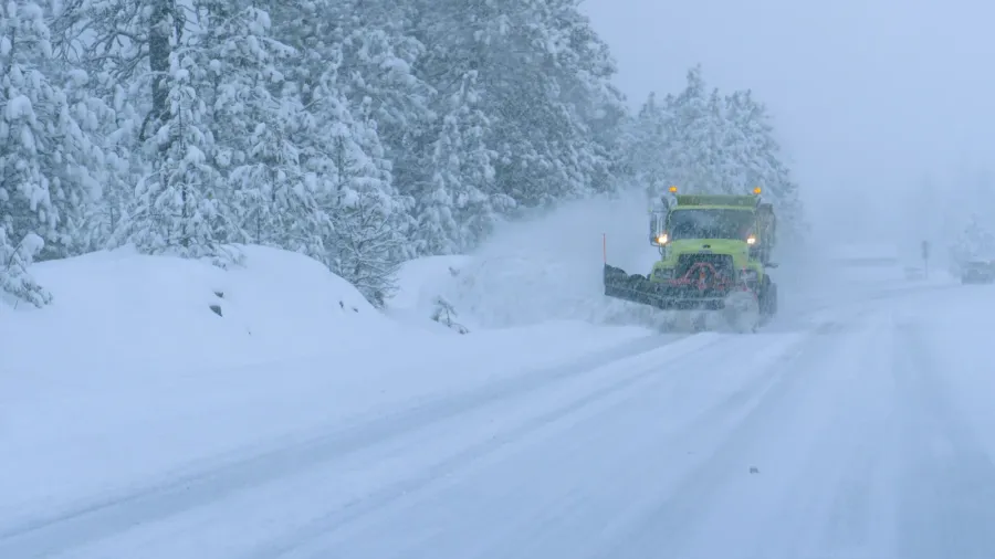 close up truck plows the snowy country road during a