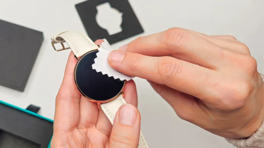 close up woman hands cleaning smart watch on white table