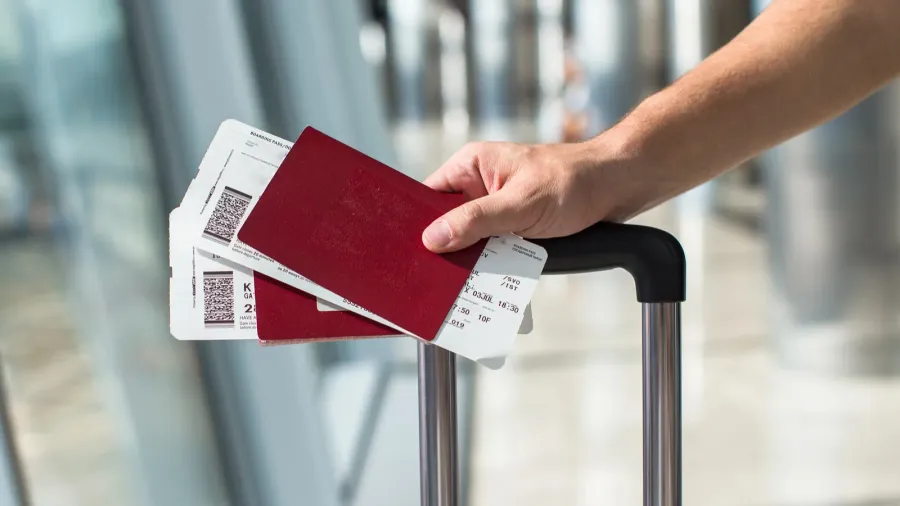 closeup of man holding passports and boarding pass at airport