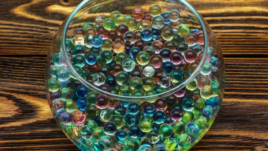 colored hydrogel balls in a glass vase on old wooden