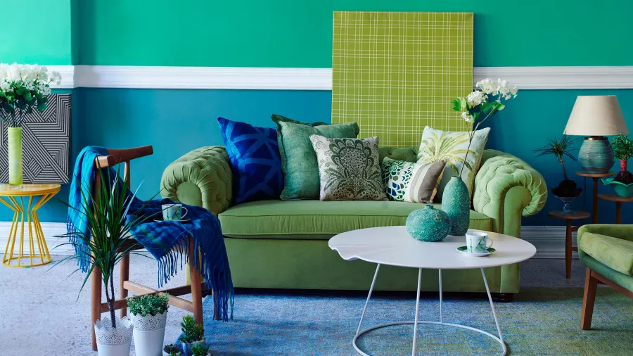 A colorful living room interior with green sofa with throw pillows, coffee table, and wooden armchair.
