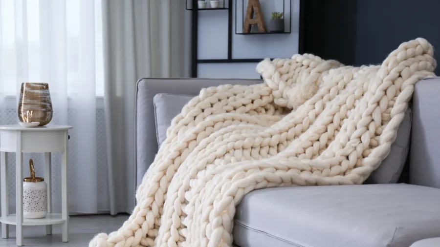 comfortable sofa with knitted plaid in living room interior design