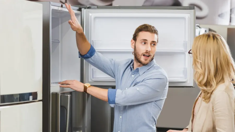 consultant talking with woman and showing fridge in home appliance