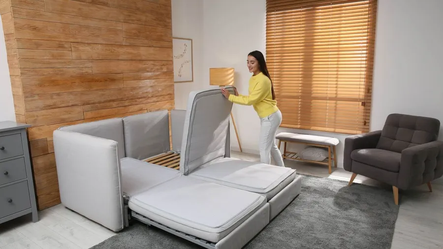 A woman unfolding a sofa into a bed.