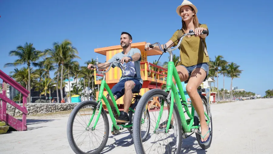 Couple of tourists riding bikes in Miami beach.